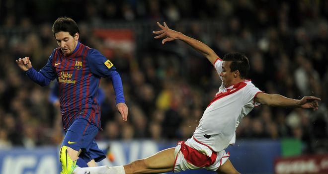 Pedro Botelho (R) makes a sliding tackle on Barcelona's Lionel Messi (L)