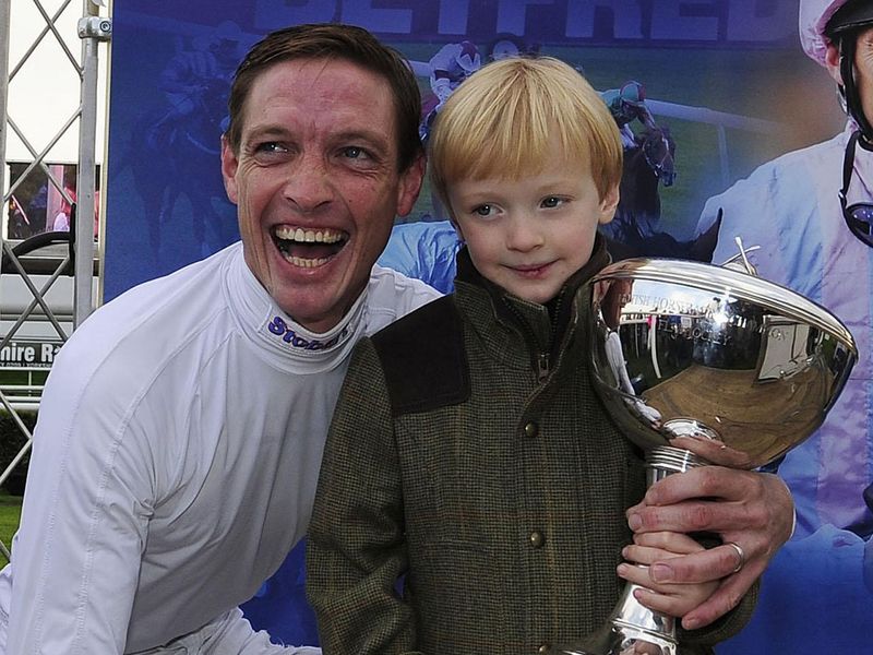 Richard Hughes and his son with the Champion Jockey trophy