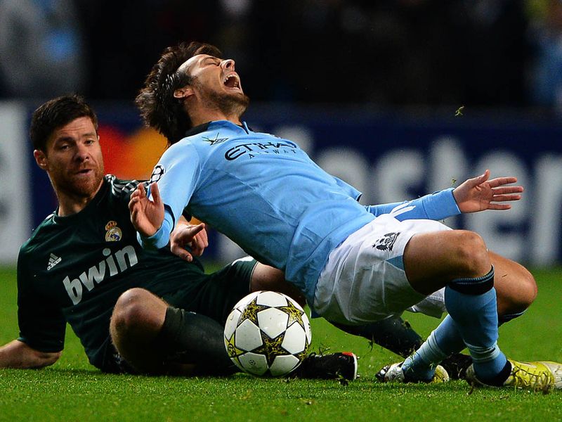 David Silva feels the full force of former Liverpool midfielder Xabi Alonso. His international team-mate picks up a yellow card for the challenge.