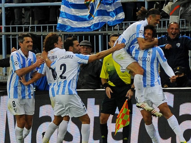 Roque Santa Cruz is mobbed by his team-mates after putting Malaga 2-0 in front against Porto