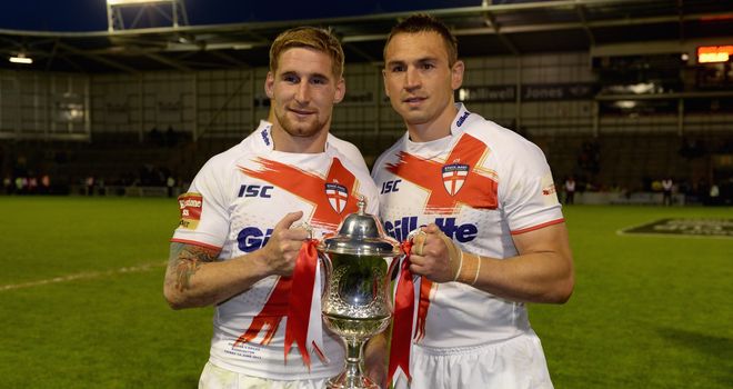 Sam Tomkins (l) and England captain Kevin Sinfield lift the trophy after victory at The Halliwell Jones Stadium