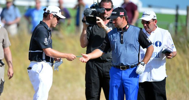 Louis Oosthuizen hands Graeme McDowell his card after being forced to quit