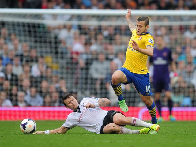 Wilshere jumps over Riise's challenge.