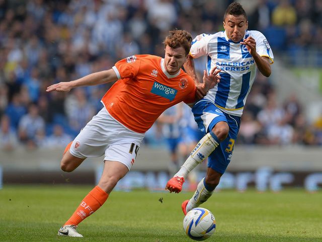 Andrew Halliday of Blackpool holds off a challenge from Jesse Lingard