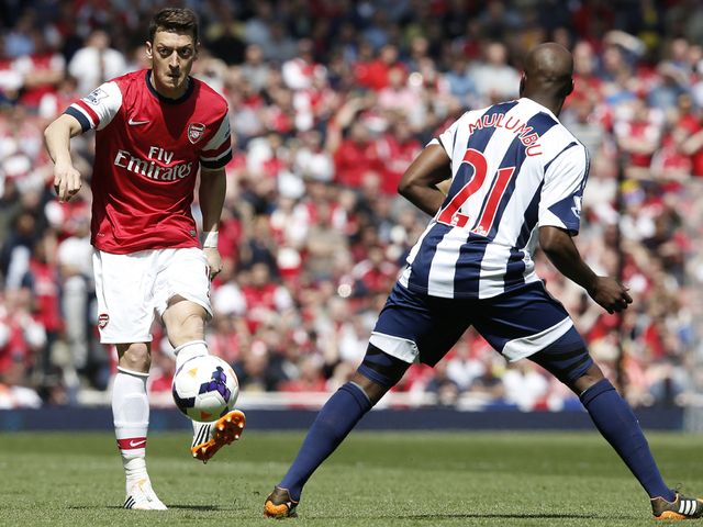 Arsenal midfielder Mesut Ozil passes the ball over West Brom's Youssouf Mulumbu