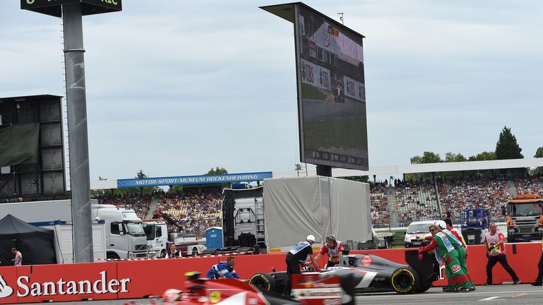 Adrian Sutil's car is recovered by the marshals as Kimi Raikkonen flashes past