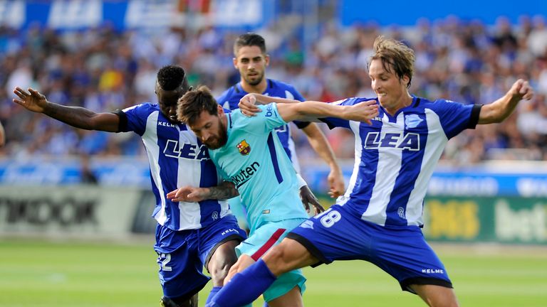 Lionel Messi (C) vies with Alaves' Wakaso Mubarak (L) and midfielder Tomas Pina (R)