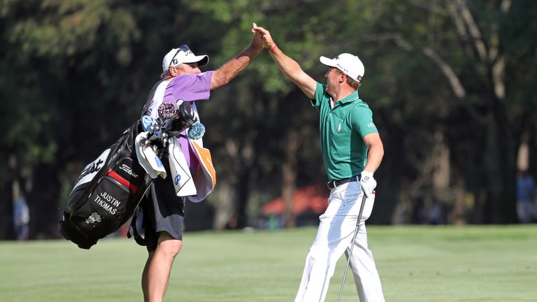 Justin Thomas celebrates with his caddie after his eagle at the 18th