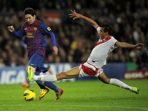 Image of Pedro Botelho (R) makes a sliding tackle on Barcelona's Lionel Messi (L)