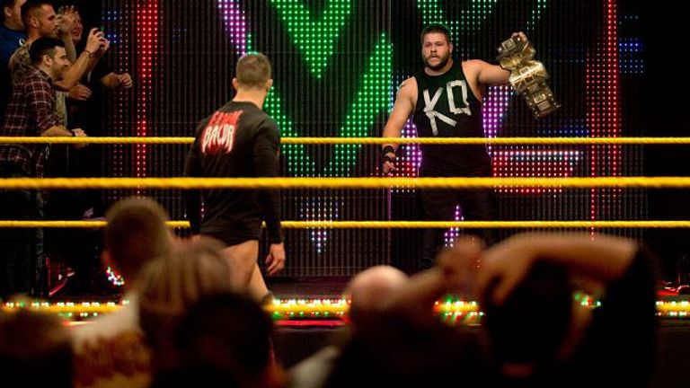 Kevin Owens holds his belt after running from Finn Balor