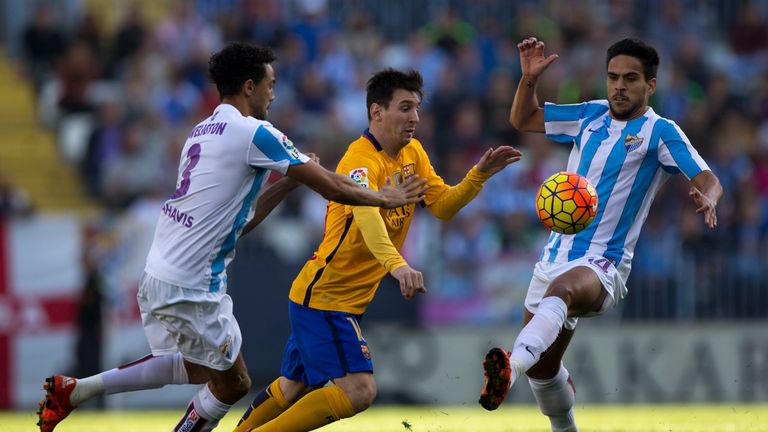 Lionel Messi (2ndL) of Barcelona tries to evade the challenges of Wellington Robson (L) and Recio of Malaga