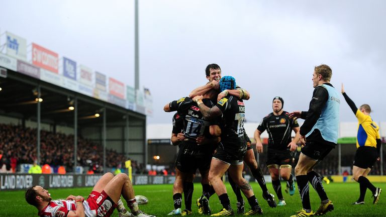 Olly Woodburn is mobbed by team-mates after scoring Exeter's third try
