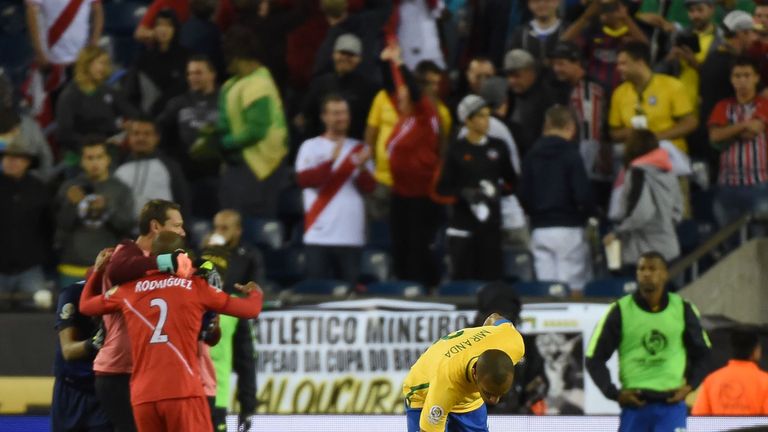 Members of Peru's national team celebrate their victory as Brazil's Miranda comforts team-mate Renato Augusto