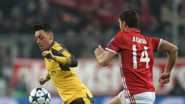 Mesut Ozil (left) takes on Bayern Munich's Xabi Alonso