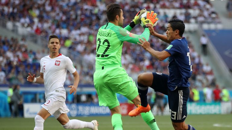 Lukasz Fabianski collects the ball under pressure from Yoshinori Muto