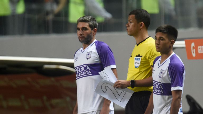 Defensor Sporting prepare their substitutions as the fourth official holds the paper numbers