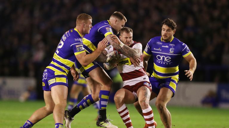Zak Hardacre of Wigan Warriors is tackled by the Warrington defence