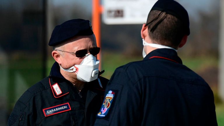 Policías italianos usan mascarillas respiratorias en un punto de control en medio del brote de coronavirus del país