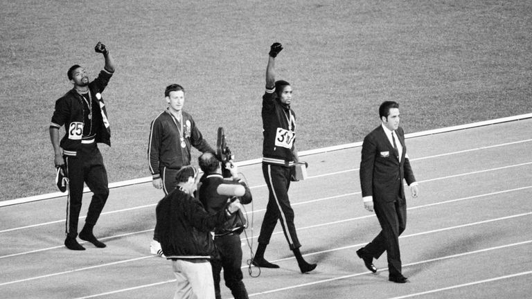 Smith (centre) and Carlos (left) continue with their raised gloved hands after walking off the podium in 1968