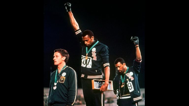 Extending gloved hands skyward in protest, Smith and John Carlos stare downward during the playing of The Star-Spangled Banner
