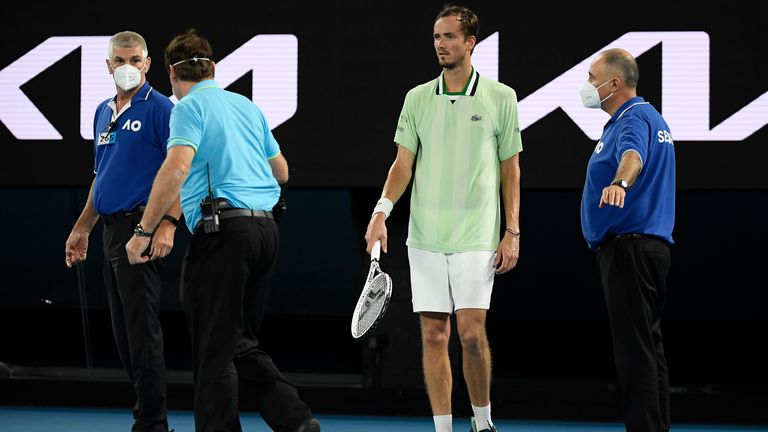Security guards stand close to Medvedev after a protester interrupted play by jumping onto the court