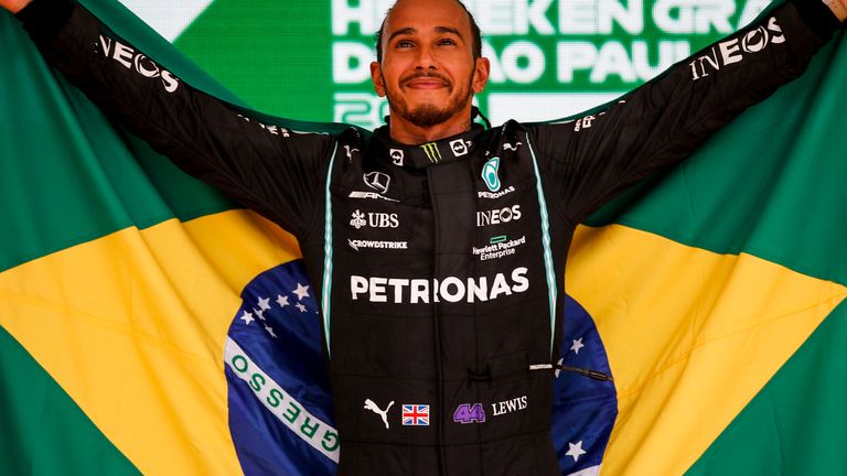     Lewis Hamilton carrega a bandeira brasileira após vencer o GP do Brasil no ano passado