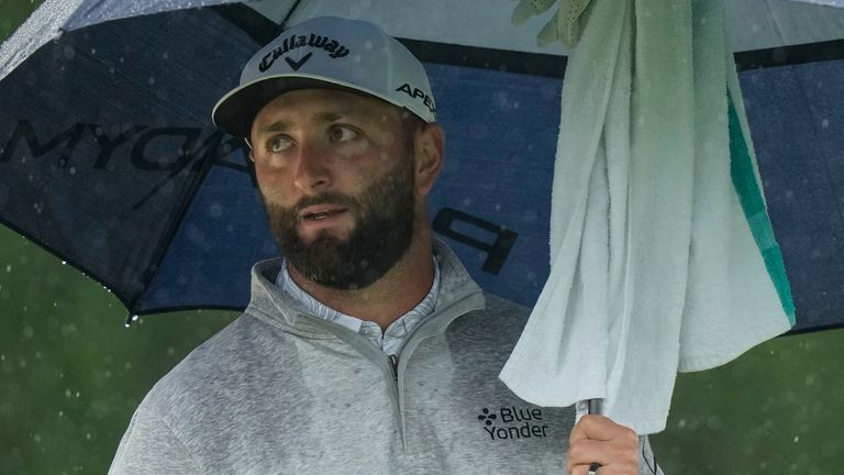 Jon Rahm waits to play in the rain on the 18th hole during the weather-delayed second round of The Masters