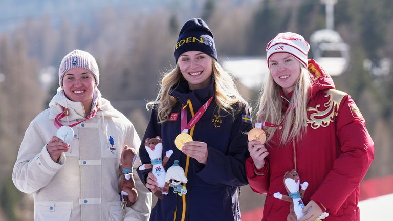 Bronze medalist Varvara Voronchikhina of Russia (right) poses on the podium of the alpine skiing women's downhill standing competition.